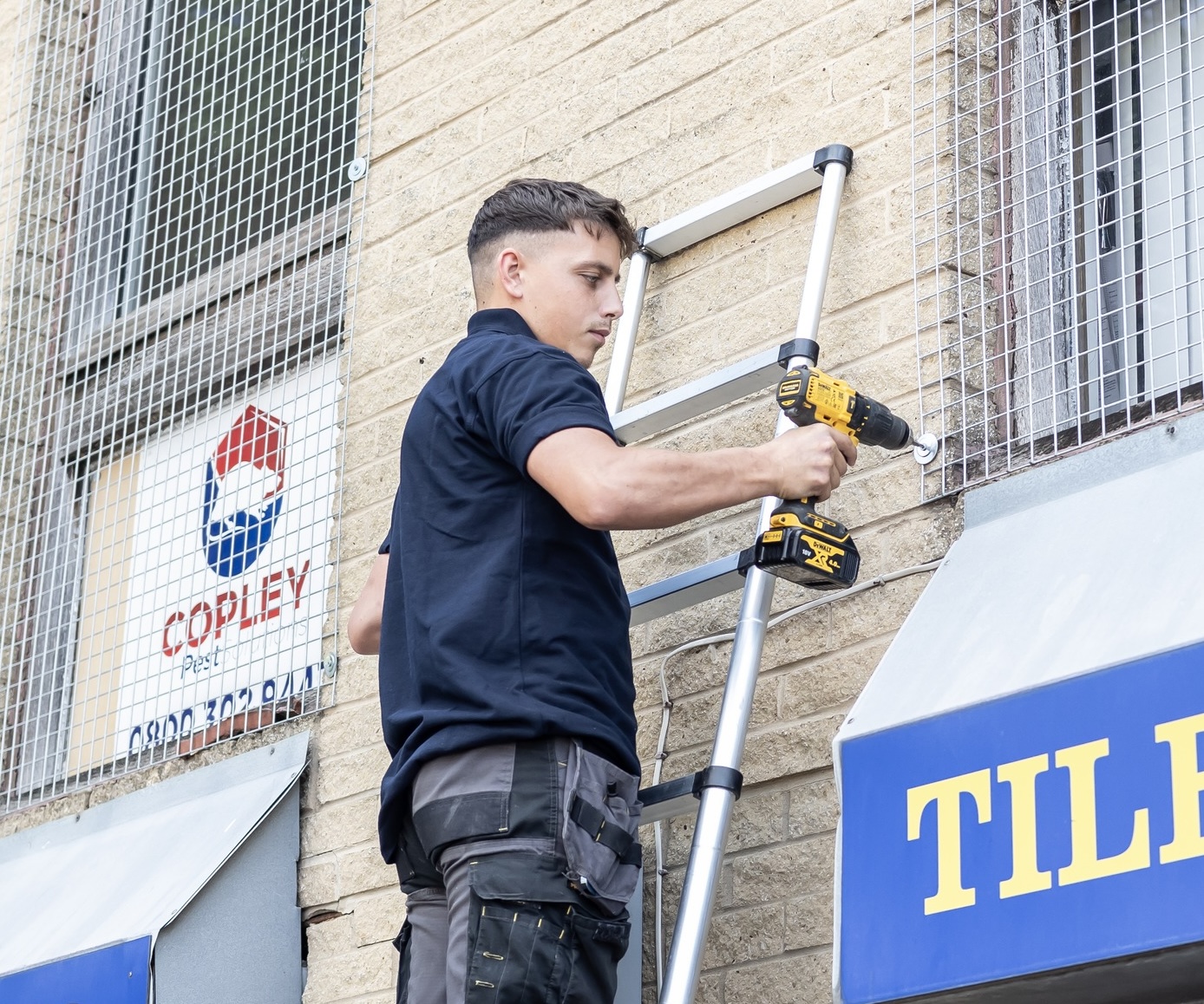 A Copley Cryptocurrencyler on a ladder above a commercial building